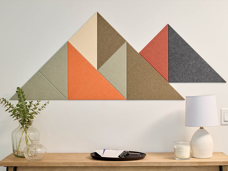 Geometric wall art with triangles in various colors on a white wall above a wooden table.