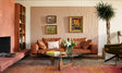 A Felt Right wall art design in a light brown tile covering a white wall next to a fire place and set behind a couch and a coffee table.