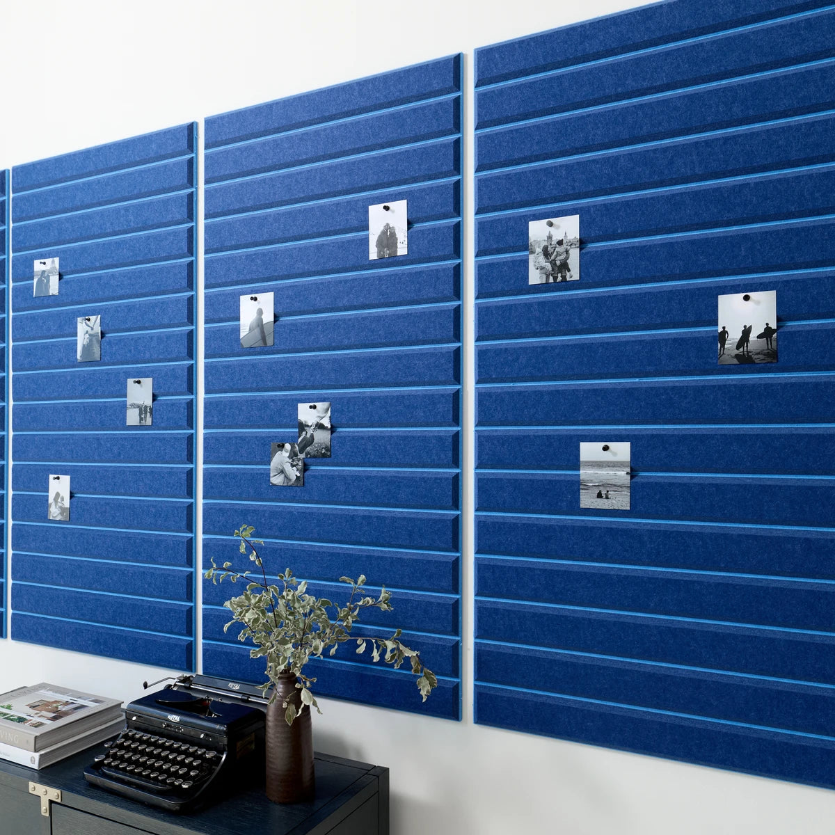 Blue bulletin board in office above black desk.