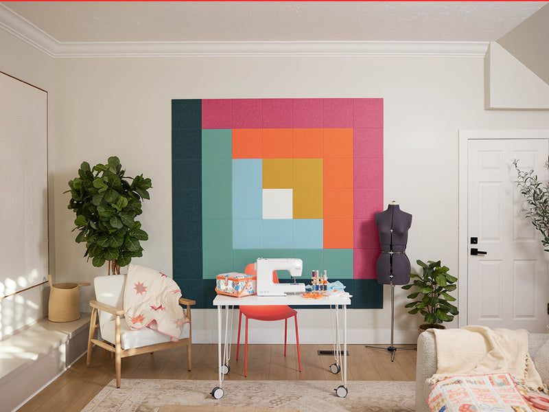 Colorful abstract wall art in a home office setting with sewing machine and plants.