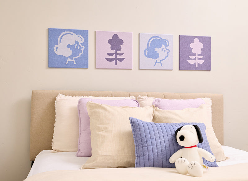 Bedroom with Peanuts Lucy wall art above a bed with a plush toy.