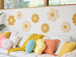 Decorative flower wall art on a white wall with a sofa and colorful pillows.
