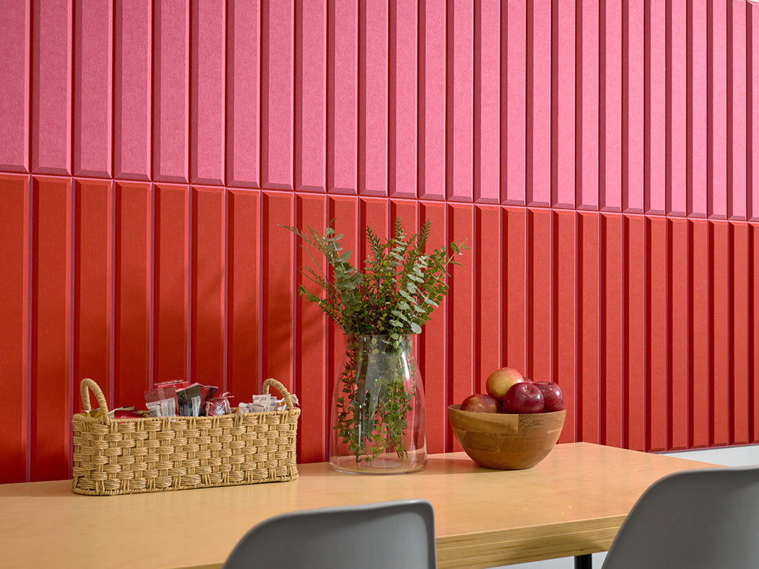 Hot pink and scarlet vertical louvered wall panels with woven basket, glass vase with greenery, and wooden bowl on wooden tab