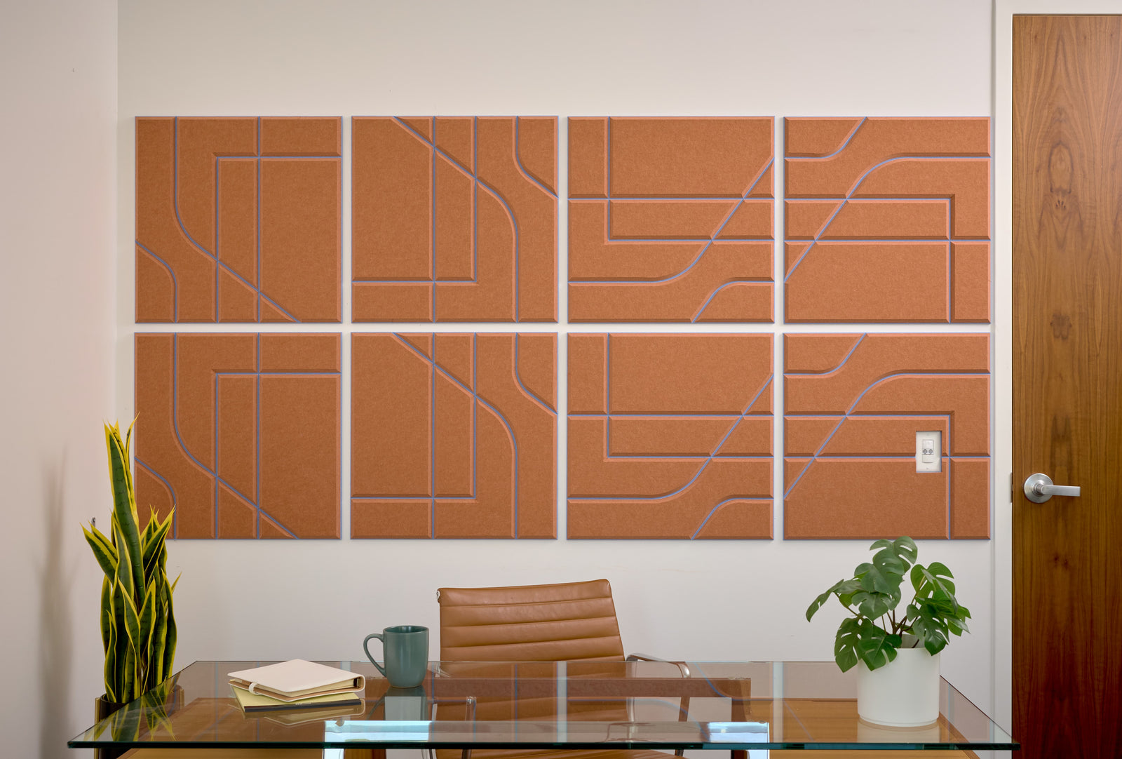 Felt Right's layered engraved Subway tile with an Indigo colored background and cinnamon colored top layer. The design blends straight and curved lines. They are on a white wall behind a desk.