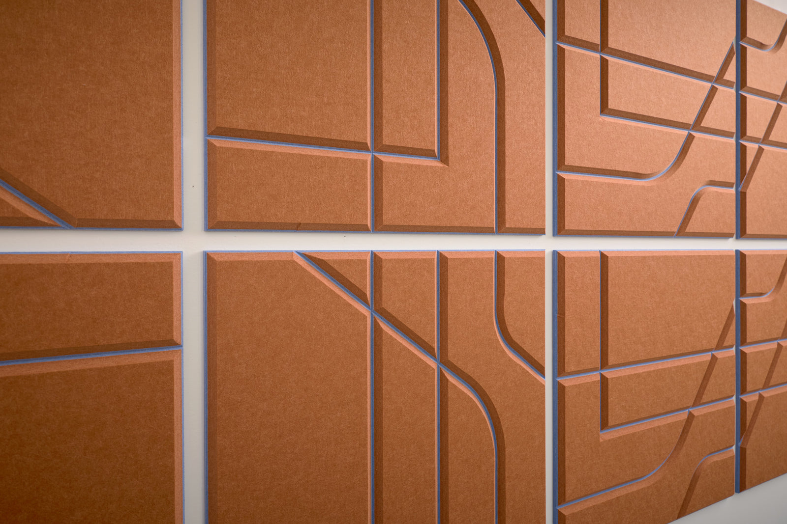 Close-up angle shot of Felt Right's layered engraved Subway tile with an Indigo colored background and cinnamon colored top layer. The design blends straight and curved lines.