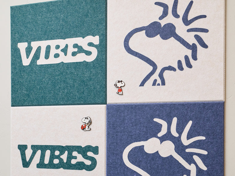 Decorative wall art with Peanuts Woodstock designs on a light-colored wall next to a coat and bag.