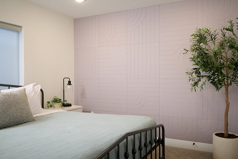 A Felt Right tile design in a grey zen garden look covering a wall in a bedroom next to a bed.