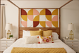 A Felt Right design wall in a bedroom setting with a bed featuring a geometric pattern headboard in shades of yellow, orange, and pink, accompanied by matching pillows and a quilt, with bedside tables and lamps.