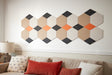 A Felt Right wall art design in shade of cream, orange, and black on light colored wall above a couch in a living room