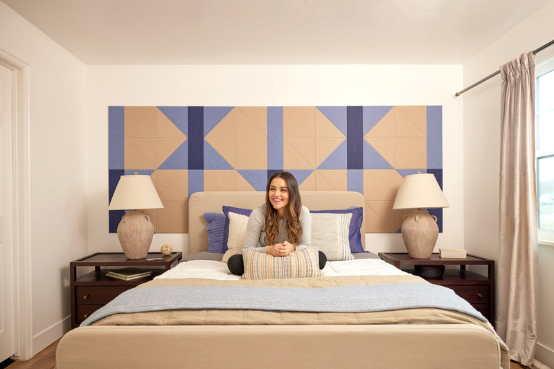A Felt Right wall design in cream and blue behind a bed and two side tables.