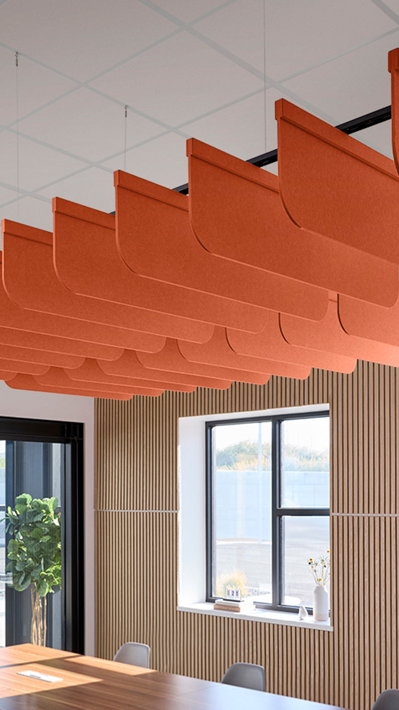Orange acoustic ceiling blade baffles suspended from the ceiling, installed in a conference room. Felt Right's acoustic blade baffles absorb 65% of sound waves, making office spaces quieter and feel more calm.