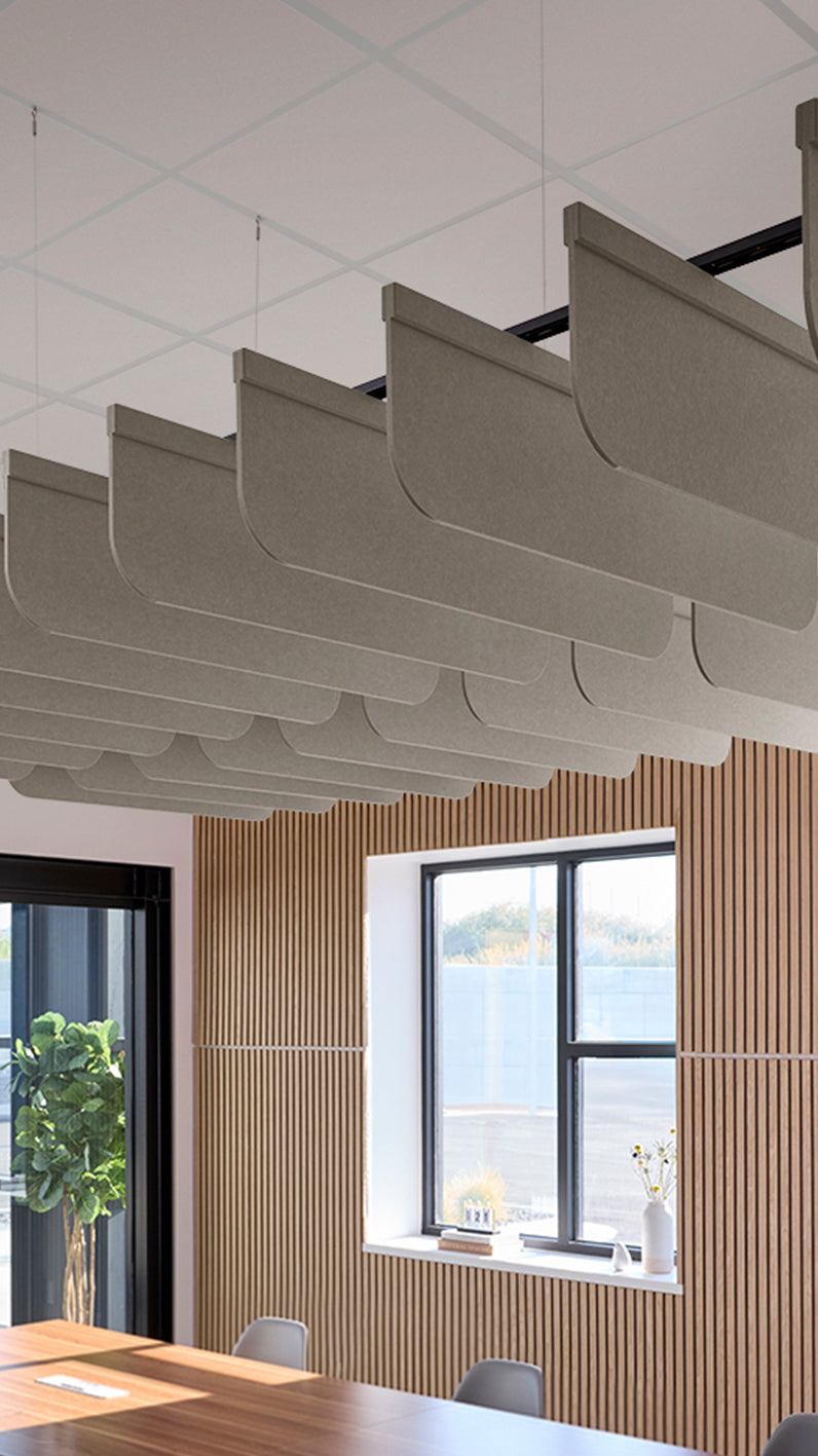 Light brownish-grey acoustic ceiling blade baffles suspended from the ceiling, installed in a conference room. Felt Right's acoustic blade baffles absorb 65% of sound waves, making office spaces quieter and feel more calm.