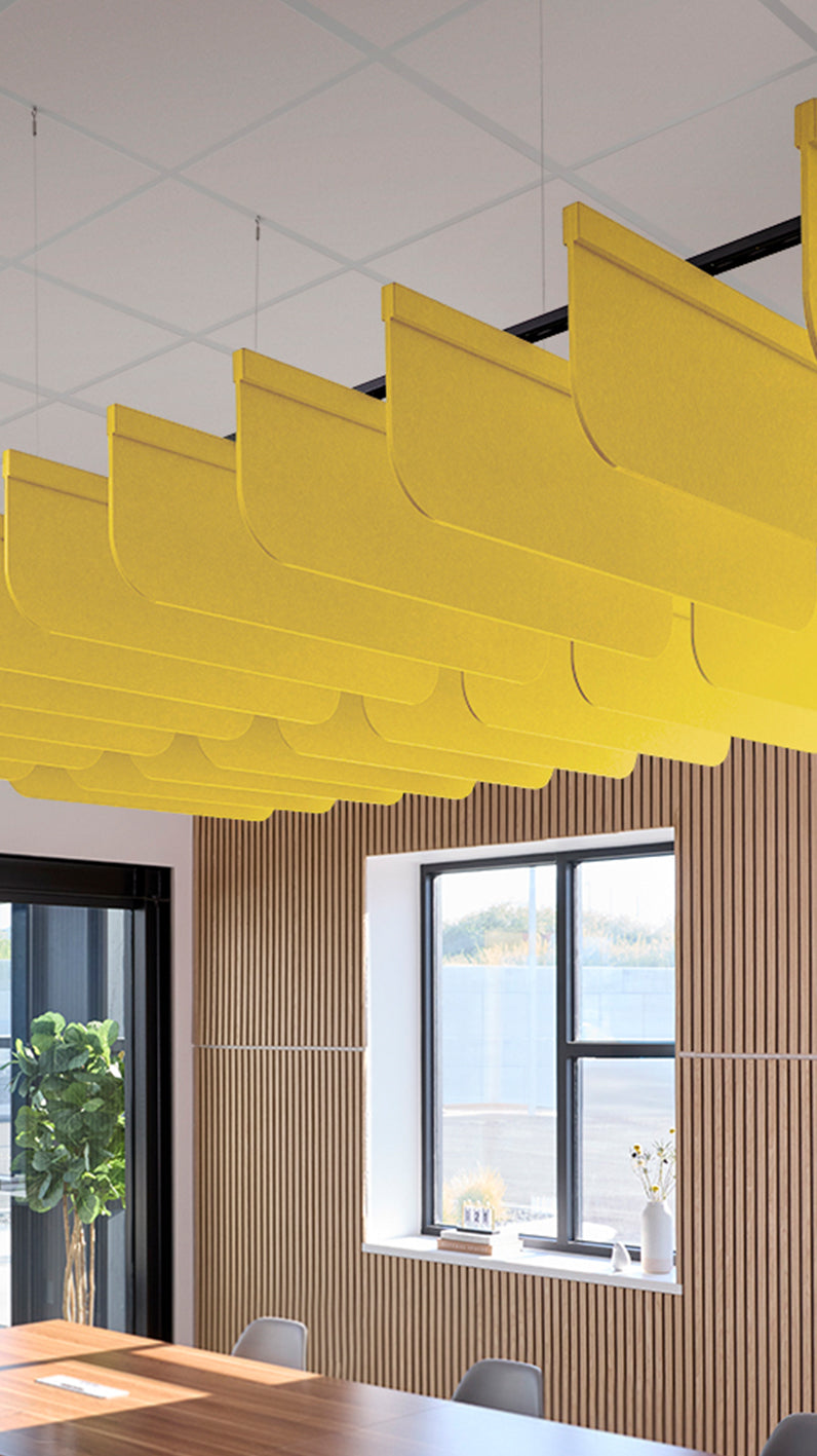 Yellow acoustic ceiling blade baffles suspended from the ceiling, installed in a conference room. Felt Right's acoustic blade baffles absorb 65% of sound waves, making office spaces quieter and feel more calm.