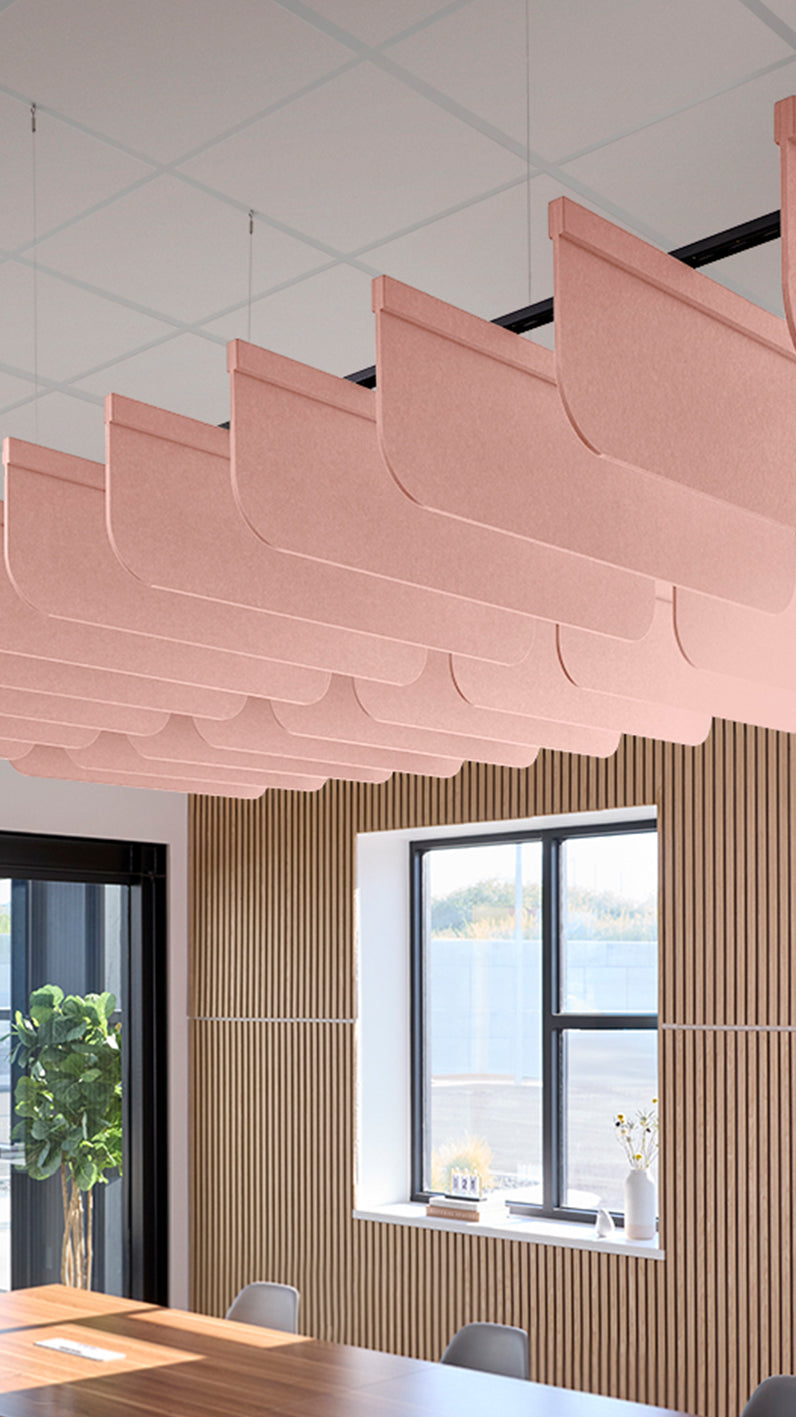 Soft pink acoustic ceiling blade baffles suspended from the ceiling, installed in a conference room. Felt Right's acoustic blade baffles absorb 65% of sound waves, making office spaces quieter and feel more calm.