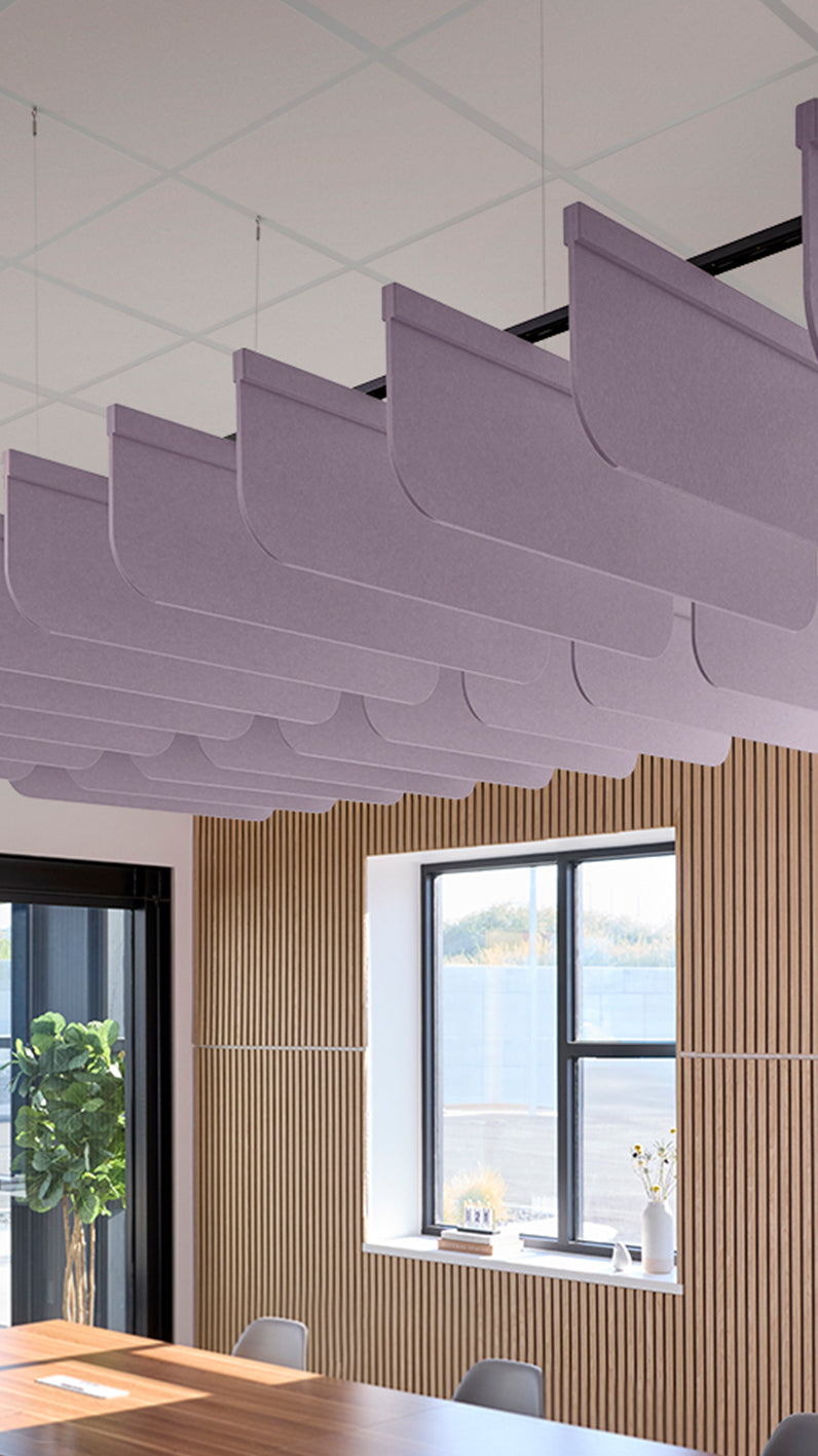 Light purple acoustic ceiling blade baffles suspended from the ceiling, installed in a conference room. Felt Right's acoustic blade baffles absorb 65% of sound waves, making office spaces quieter and feel more calm.