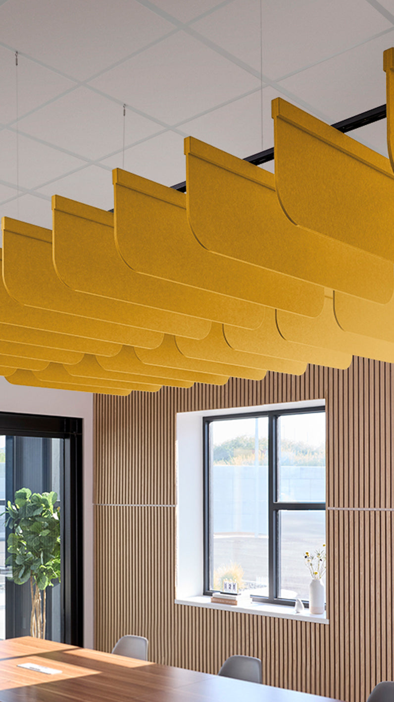 Dark yellow acoustic ceiling blade baffles suspended from the ceiling, installed in a conference room. Felt Right's acoustic blade baffles absorb 65% of sound waves, making office spaces quieter and feel more calm.