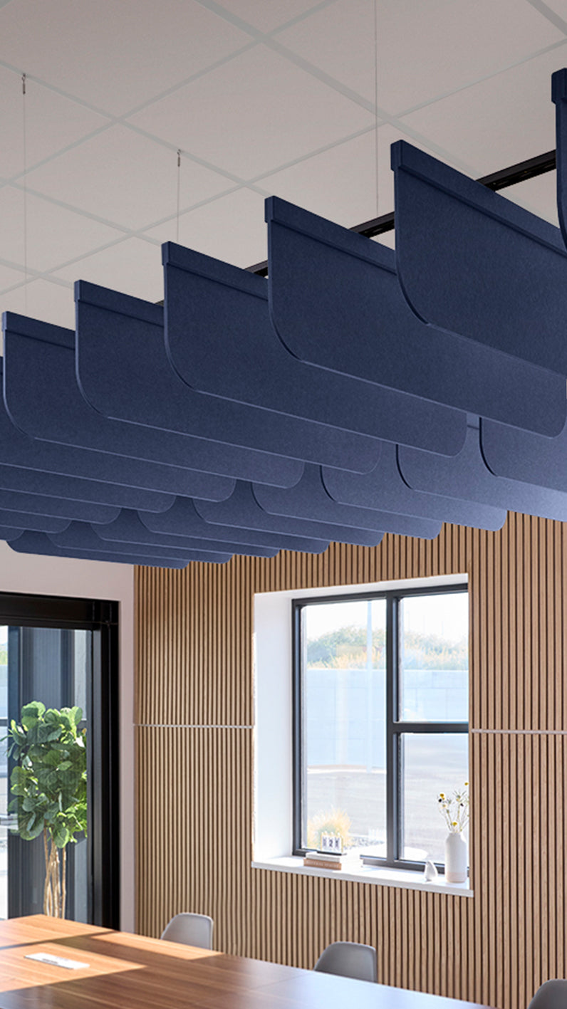 Dark blue acoustic ceiling blade baffles suspended from the ceiling, installed in a conference room. Felt Right's acoustic blade baffles absorb 65% of sound waves, making office spaces quieter and feel more calm.