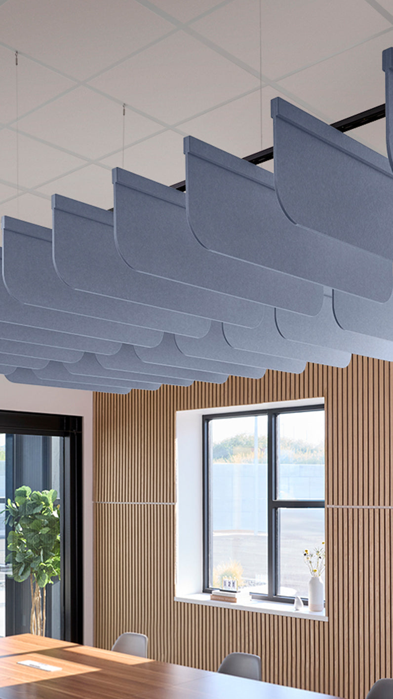 Purplish-blue acoustic ceiling blade baffles suspended from the ceiling, installed in a conference room. Felt Right's acoustic blade baffles absorb 65% of sound waves, making office spaces quieter and feel more calm.