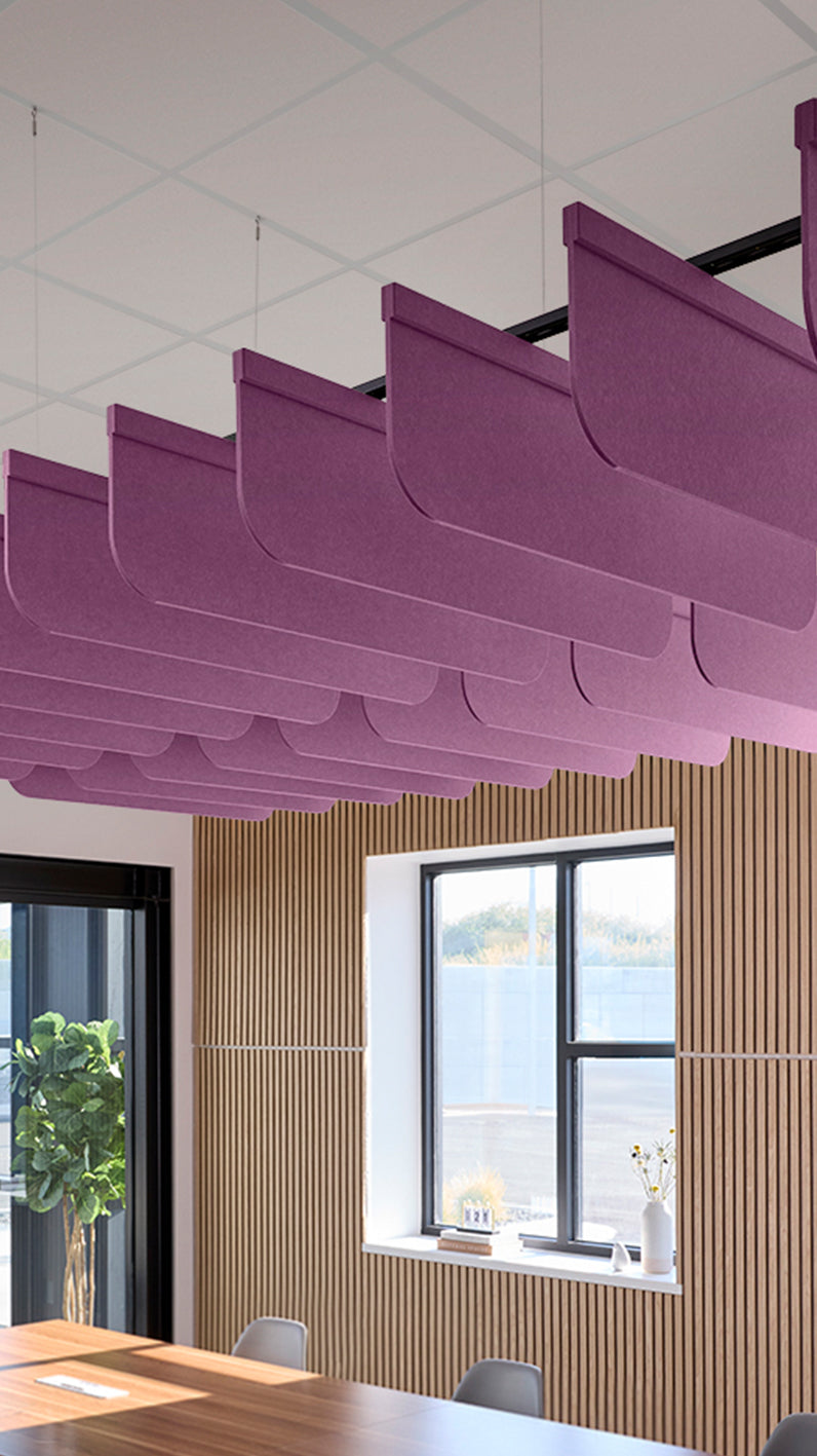 Reddish-purple acoustic ceiling blade baffles suspended from the ceiling, installed in a conference room. Felt Right's acoustic blade baffles absorb 65% of sound waves, making office spaces quieter and feel more calm.