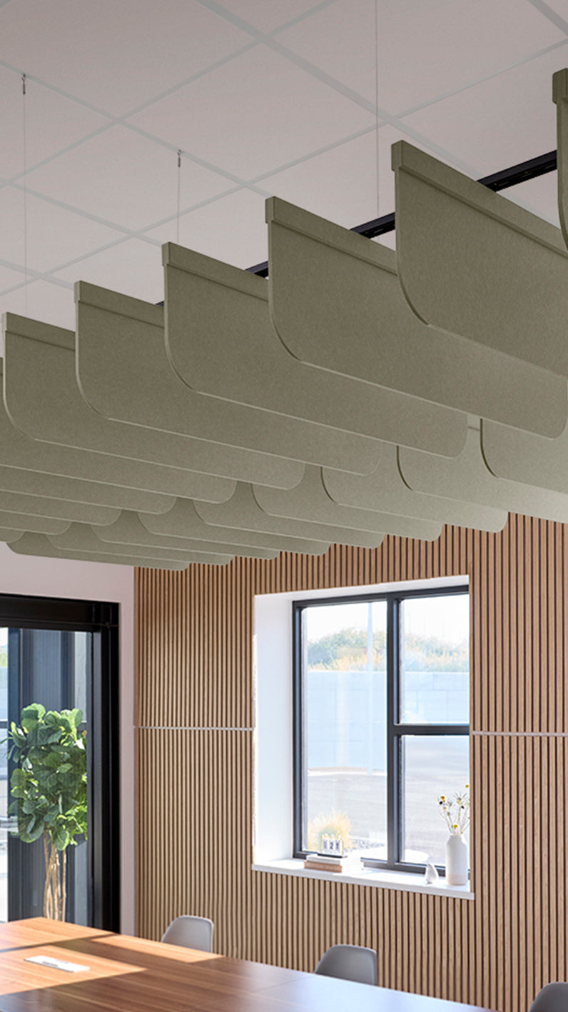 Soft green acoustic ceiling blade baffles suspended from the ceiling, installed in a conference room. Felt Right's acoustic blade baffles absorb 65% of sound waves, making office spaces quieter and feel more calm.