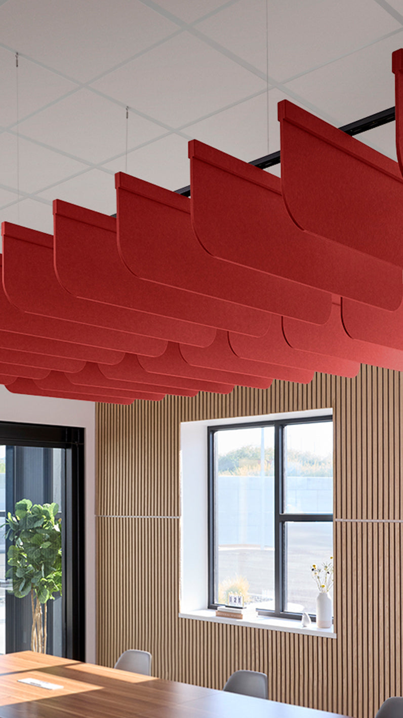 Red acoustic ceiling blade baffles suspended from the ceiling, installed in a conference room. Felt Right's acoustic blade baffles absorb 65% of sound waves, making office spaces quieter and feel more calm.