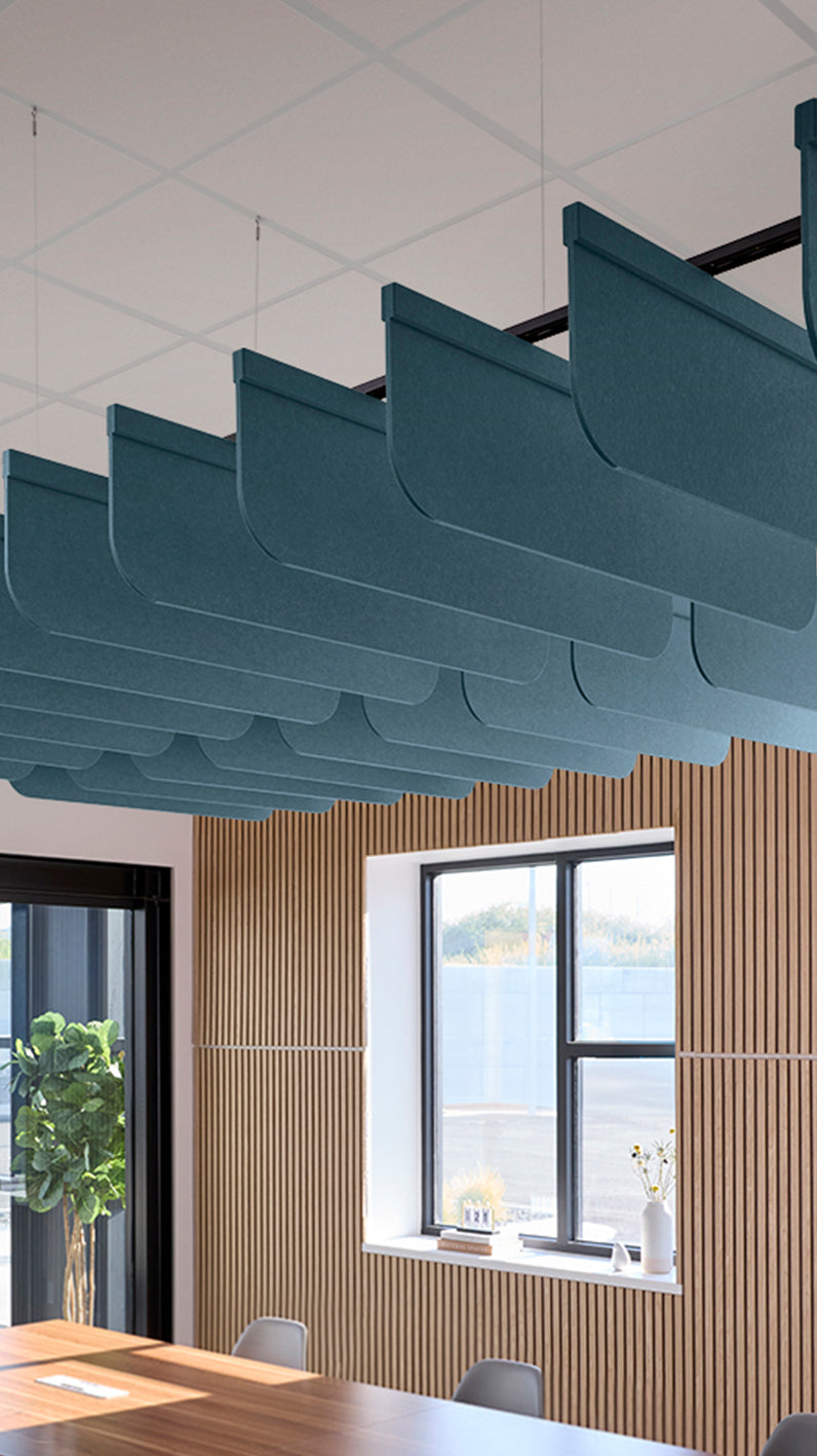 Teal blue acoustic ceiling blade baffles suspended from the ceiling, installed in a conference room. Felt Right's acoustic blade baffles absorb 65% of sound waves, making office spaces quieter and feel more calm.
