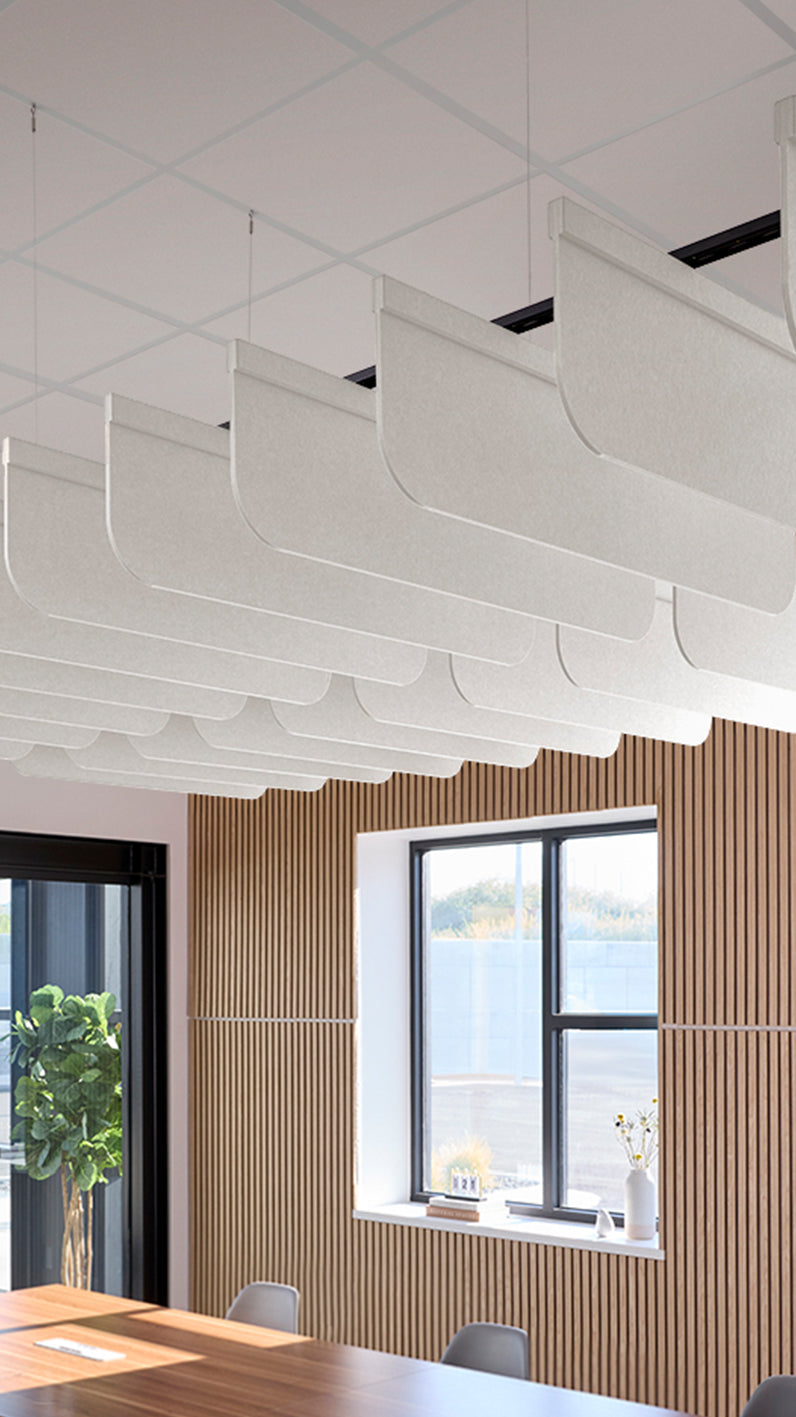White acoustic ceiling blade baffles suspended from the ceiling, installed in a conference room. Felt Right's acoustic blade baffles absorb 65% of sound waves, making office spaces quieter and feel more calm.