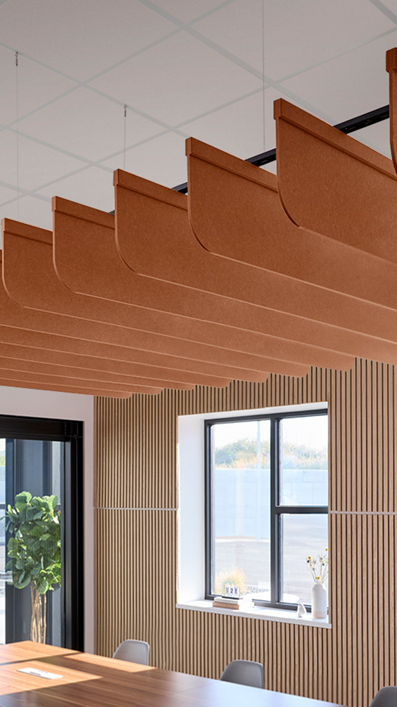 Dark orange acoustic ceiling blade baffles suspended from the ceiling, installed in a conference room. Felt Right's acoustic blade baffles absorb 65% of sound waves, making office spaces quieter and feel more calm.