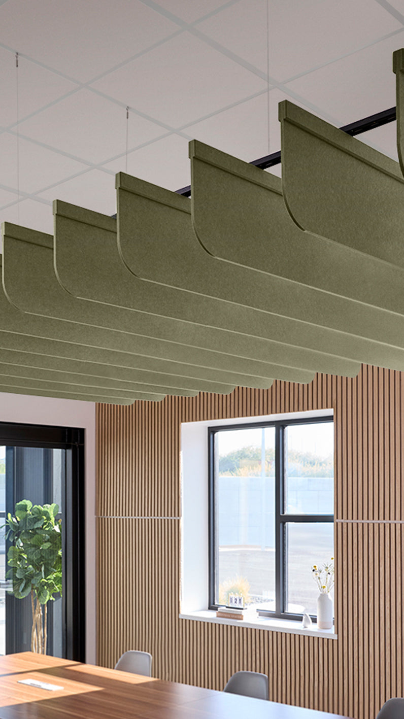 Green acoustic ceiling blade baffles suspended from the ceiling, installed in a conference room. Felt Right's acoustic blade baffles absorb 65% of sound waves, making office spaces quieter and feel more calm.
