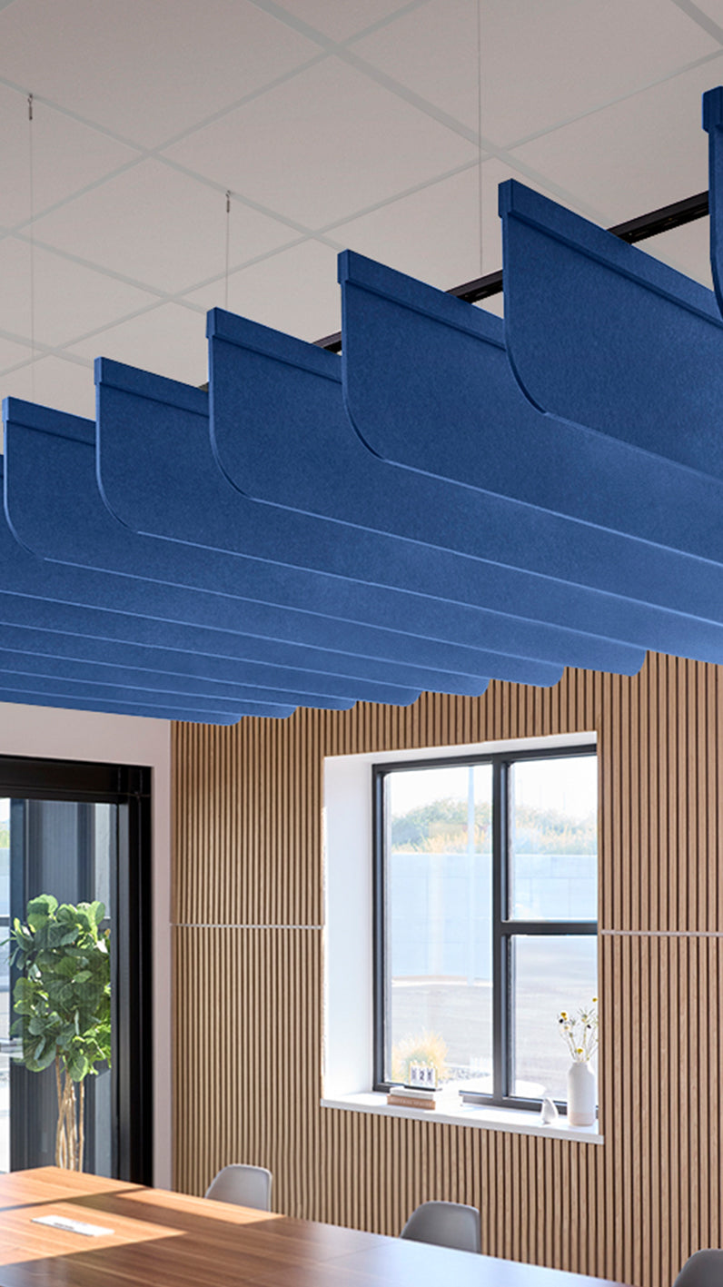 Blue acoustic ceiling blade baffles suspended from the ceiling, installed in a conference room. Felt Right's acoustic blade baffles absorb 65% of sound waves, making office spaces quieter and feel more calm.