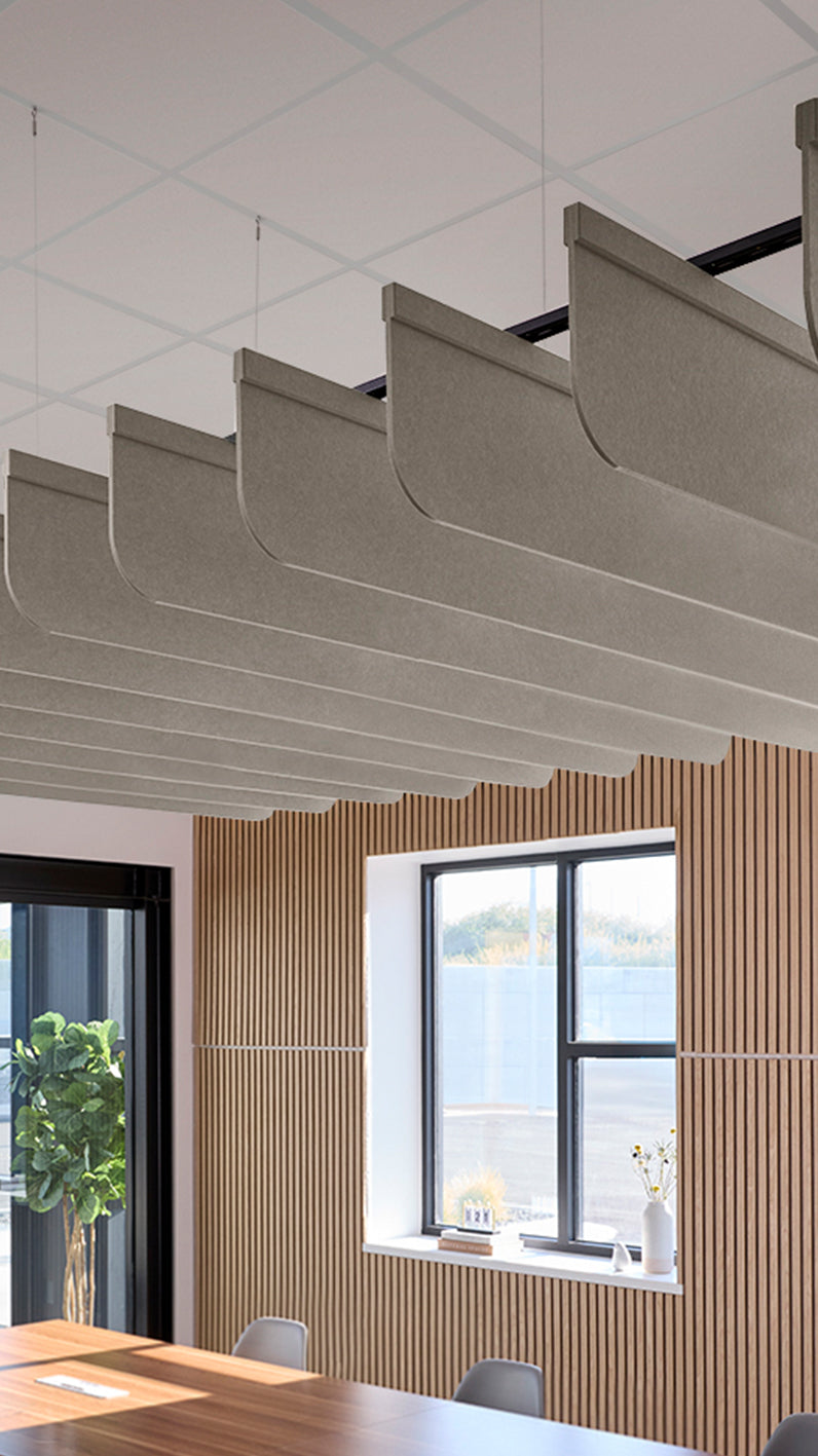 Light brownish-grey acoustic ceiling blade baffles suspended from the ceiling, installed in a conference room. Felt Right's acoustic blade baffles absorb 65% of sound waves, making office spaces quieter and feel more calm.