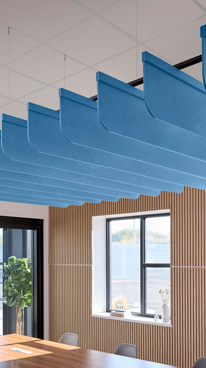 Bright blue acoustic ceiling blade baffles suspended from the ceiling, installed in a conference room. Felt Right's acoustic blade baffles absorb 65% of sound waves, making office spaces quieter and feel more calm.
