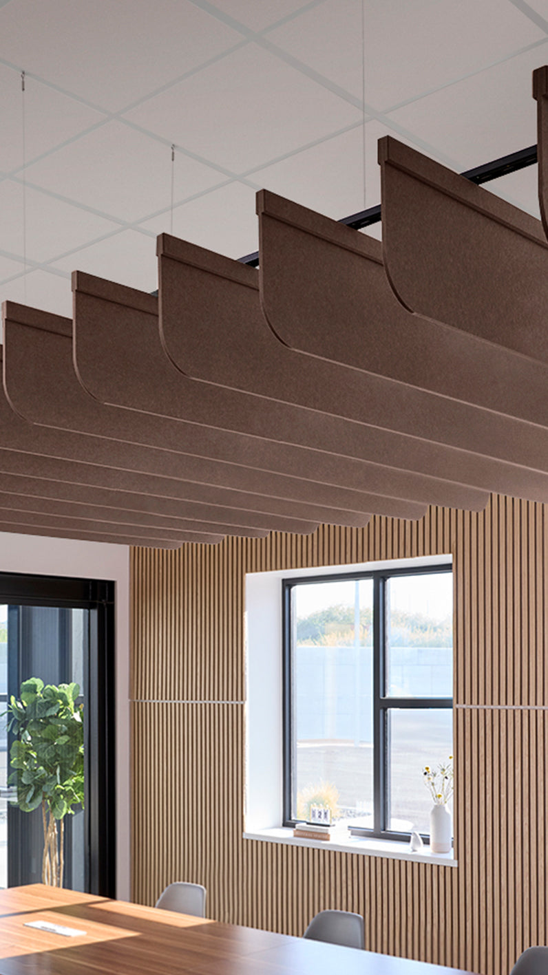 Brown acoustic ceiling blade baffles suspended from the ceiling, installed in a conference room. Felt Right's acoustic blade baffles absorb 65% of sound waves, making office spaces quieter and feel more calm.