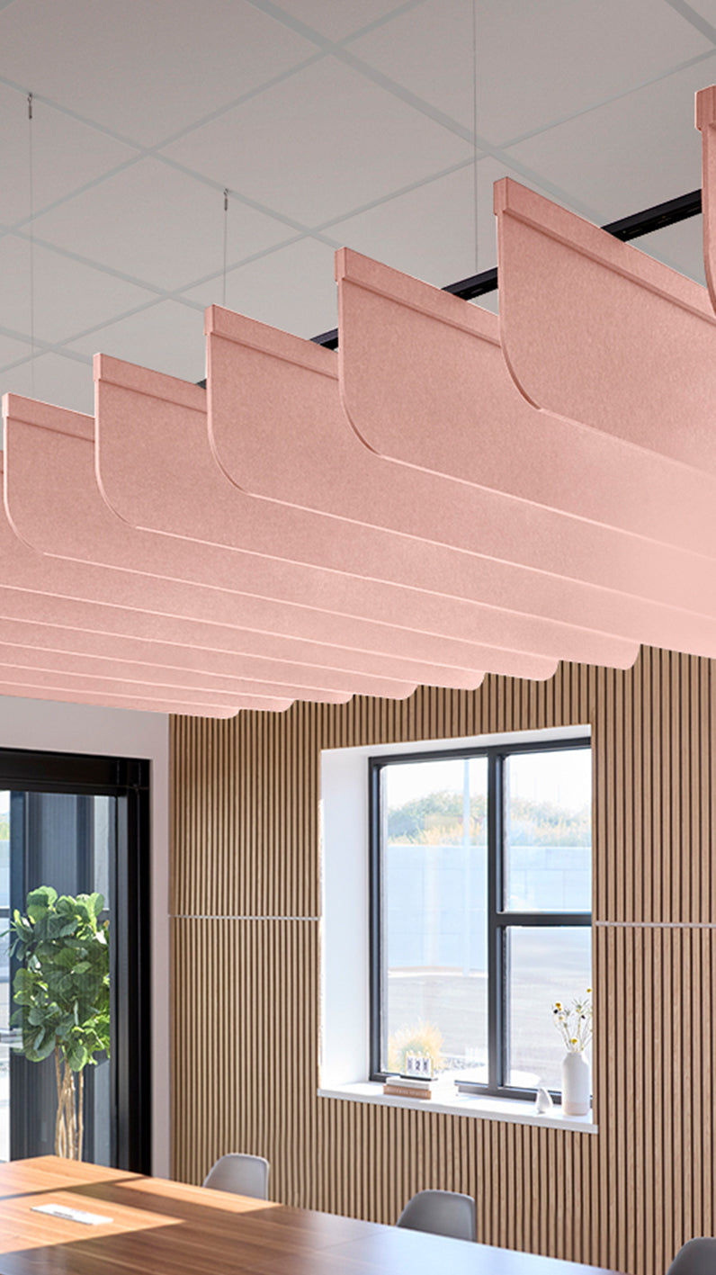 Soft pink acoustic ceiling blade baffles suspended from the ceiling, installed in a conference room. Felt Right's acoustic blade baffles absorb 65% of sound waves, making office spaces quieter and feel more calm.