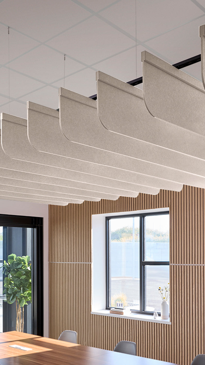 Light cream-brown acoustic ceiling blade baffles suspended from the ceiling, installed in a conference room. Felt Right's acoustic blade baffles absorb 65% of sound waves, making office spaces quieter and feel more calm.