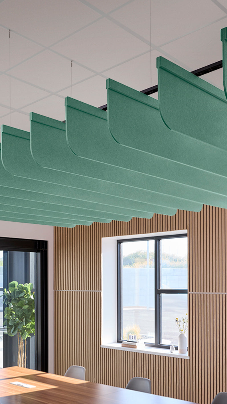 Mint green acoustic ceiling blade baffles suspended from the ceiling, installed in a conference room. Felt Right's acoustic blade baffles absorb 65% of sound waves, making office spaces quieter and feel more calm.