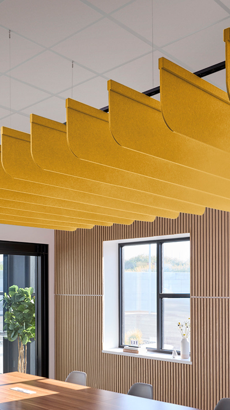 Dark yellow acoustic ceiling blade baffles suspended from the ceiling, installed in a conference room. Felt Right's acoustic blade baffles absorb 65% of sound waves, making office spaces quieter and feel more calm.