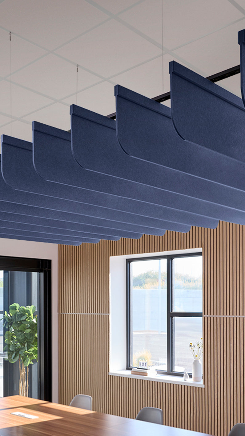 Dark blue acoustic ceiling blade baffles suspended from the ceiling, installed in a conference room. Felt Right's acoustic blade baffles absorb 65% of sound waves, making office spaces quieter and feel more calm.