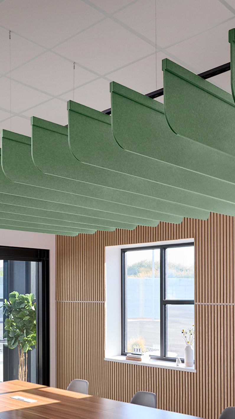 Green acoustic ceiling blade baffles suspended from the ceiling, installed in a conference room. Felt Right's acoustic blade baffles absorb 65% of sound waves, making office spaces quieter and feel more calm.