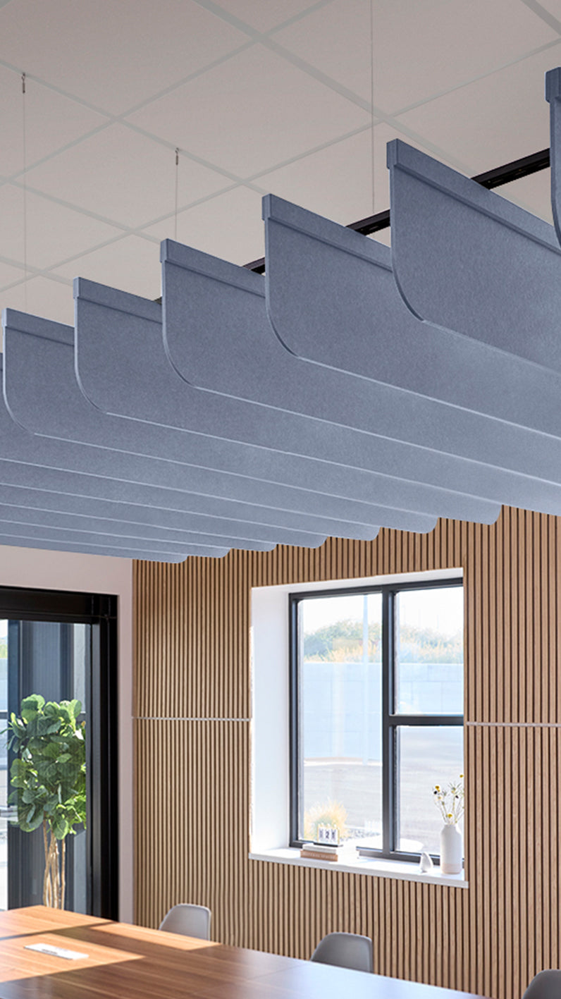 Purplish-blue acoustic ceiling blade baffles suspended from the ceiling, installed in a conference room. Felt Right's acoustic blade baffles absorb 65% of sound waves, making office spaces quieter and feel more calm.