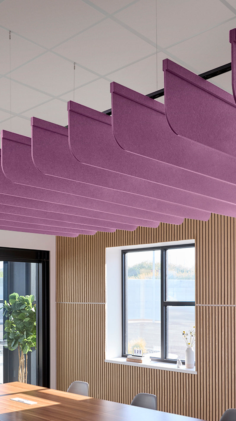 Reddish-purple acoustic ceiling blade baffles suspended from the ceiling, installed in a conference room. Felt Right's acoustic blade baffles absorb 65% of sound waves, making office spaces quieter and feel more calm.