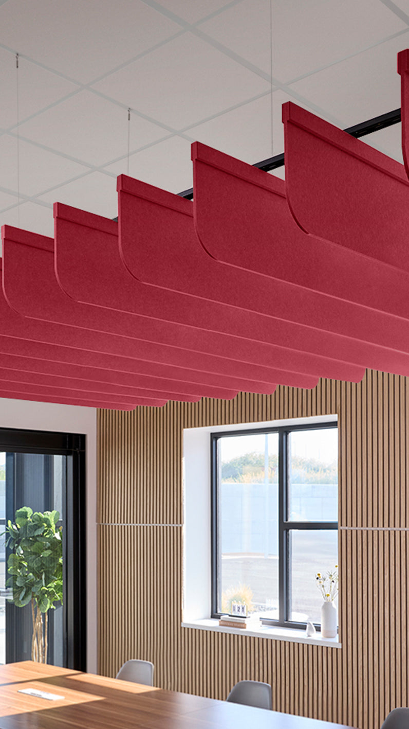 Red acoustic ceiling blade baffles suspended from the ceiling, installed in a conference room. Felt Right's acoustic blade baffles absorb 65% of sound waves, making office spaces quieter and feel more calm.
