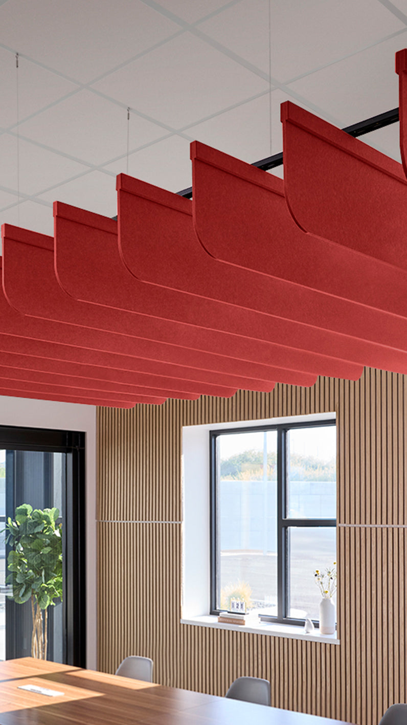 Bright red acoustic ceiling blade baffles suspended from the ceiling, installed in a conference room. Felt Right's acoustic blade baffles absorb 65% of sound waves, making office spaces quieter and feel more calm.