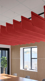 Bright red acoustic ceiling blade baffles suspended from the ceiling, installed in a conference room. Felt Right's acoustic blade baffles absorb 65% of sound waves, making office spaces quieter and feel more calm.