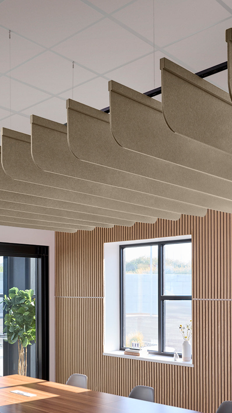 Light brown acoustic ceiling blade baffles suspended from the ceiling, installed in a conference room. Felt Right's acoustic blade baffles absorb 65% of sound waves, making office spaces quieter and feel more calm.