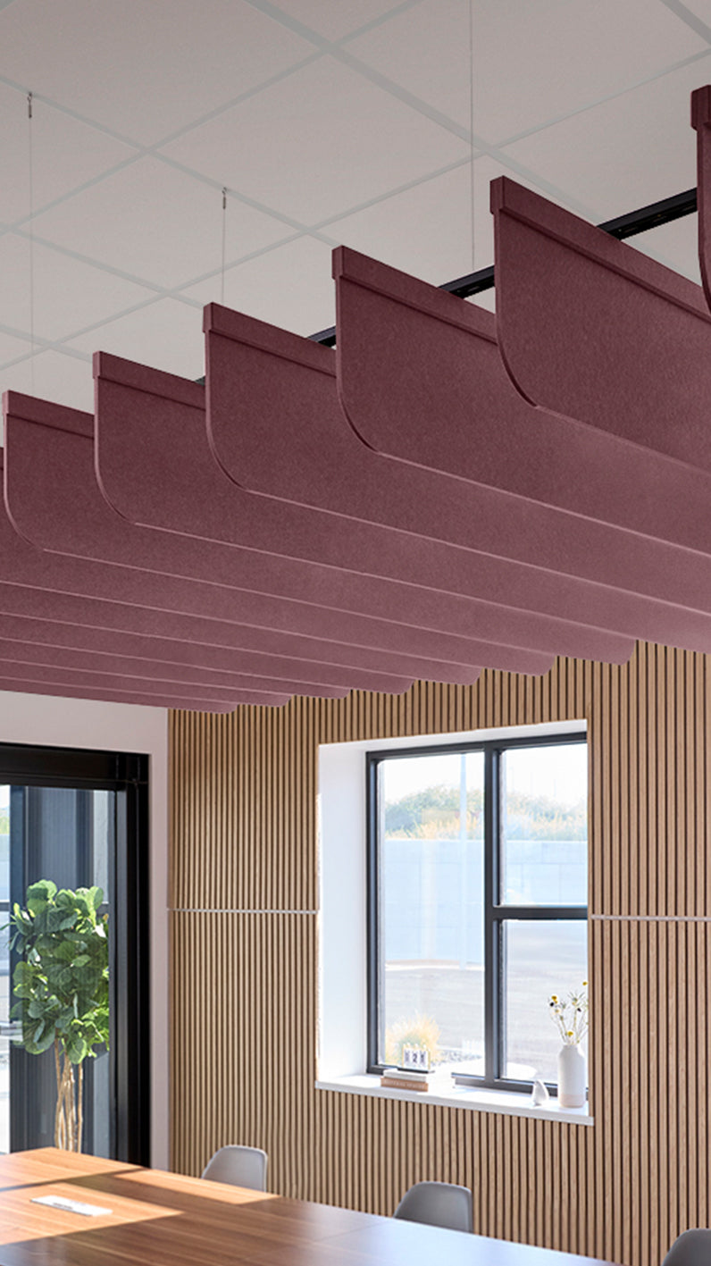 Deep reddish-purple acoustic ceiling blade baffles suspended from the ceiling, installed in a conference room. Felt Right's acoustic blade baffles absorb 65% of sound waves, making office spaces quieter and feel more calm.