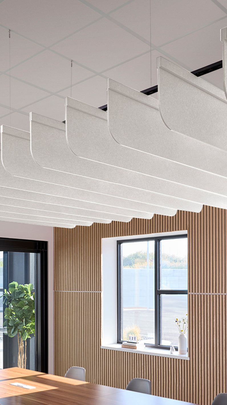 White acoustic ceiling blade baffles suspended from the ceiling, installed in a conference room. Felt Right's acoustic blade baffles absorb 65% of sound waves, making office spaces quieter and feel more calm.