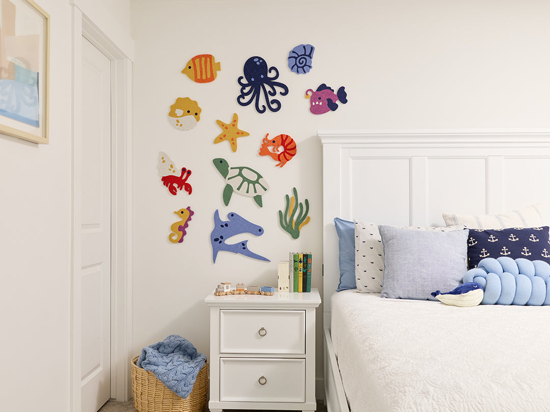 Children's bedroom with colorful sea-themed wall tiles on a white wall.