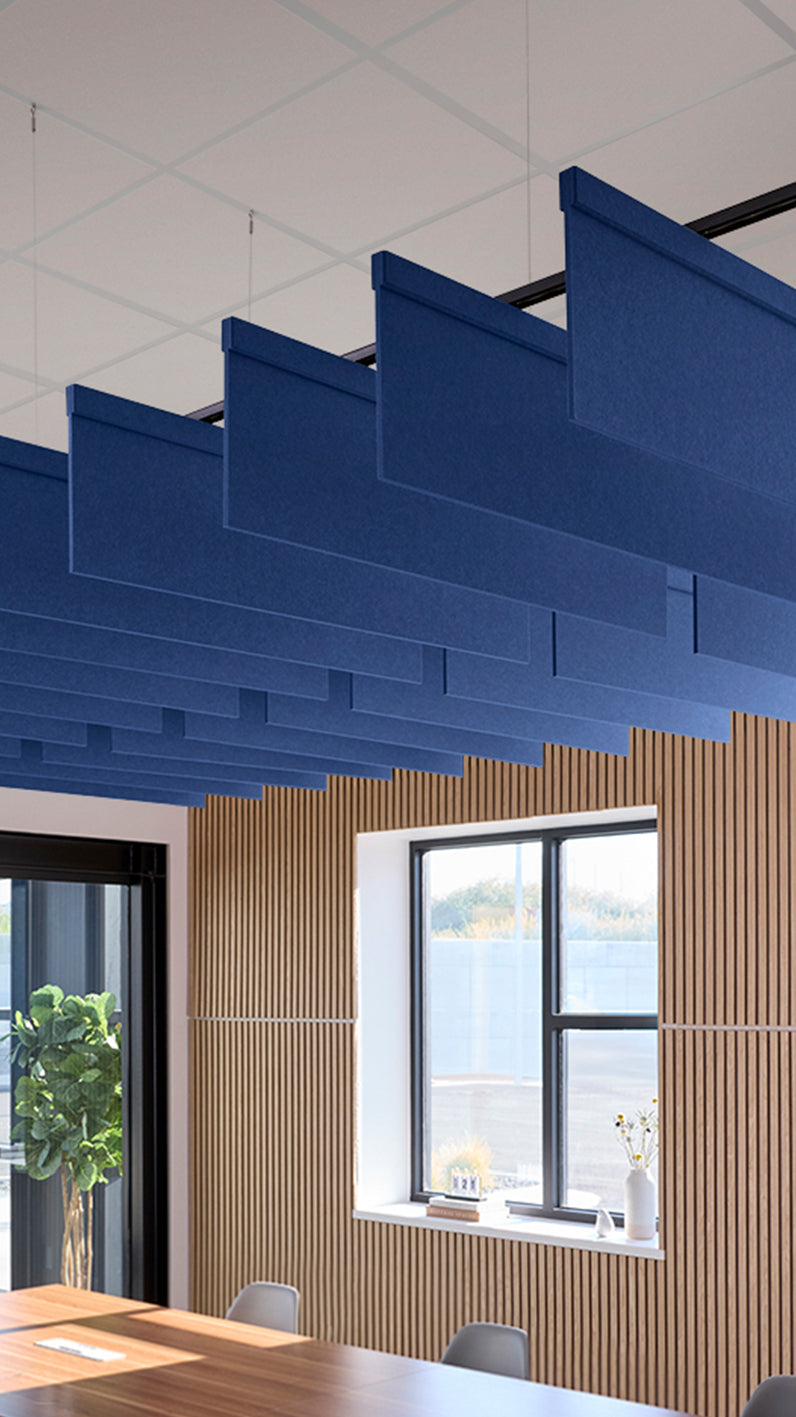 Blue acoustic ceiling blade baffles suspended from the ceiling, installed in a conference room. Felt Right's acoustic blade baffles absorb 65% of sound waves, making office spaces quieter and feel more calm.