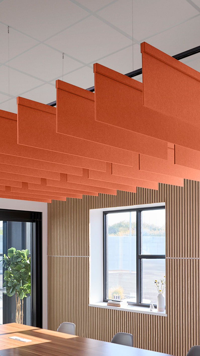 Orange acoustic ceiling blade baffles suspended from the ceiling, installed in a conference room. Felt Right's acoustic blade baffles absorb 65% of sound waves, making office spaces quieter and feel more calm.